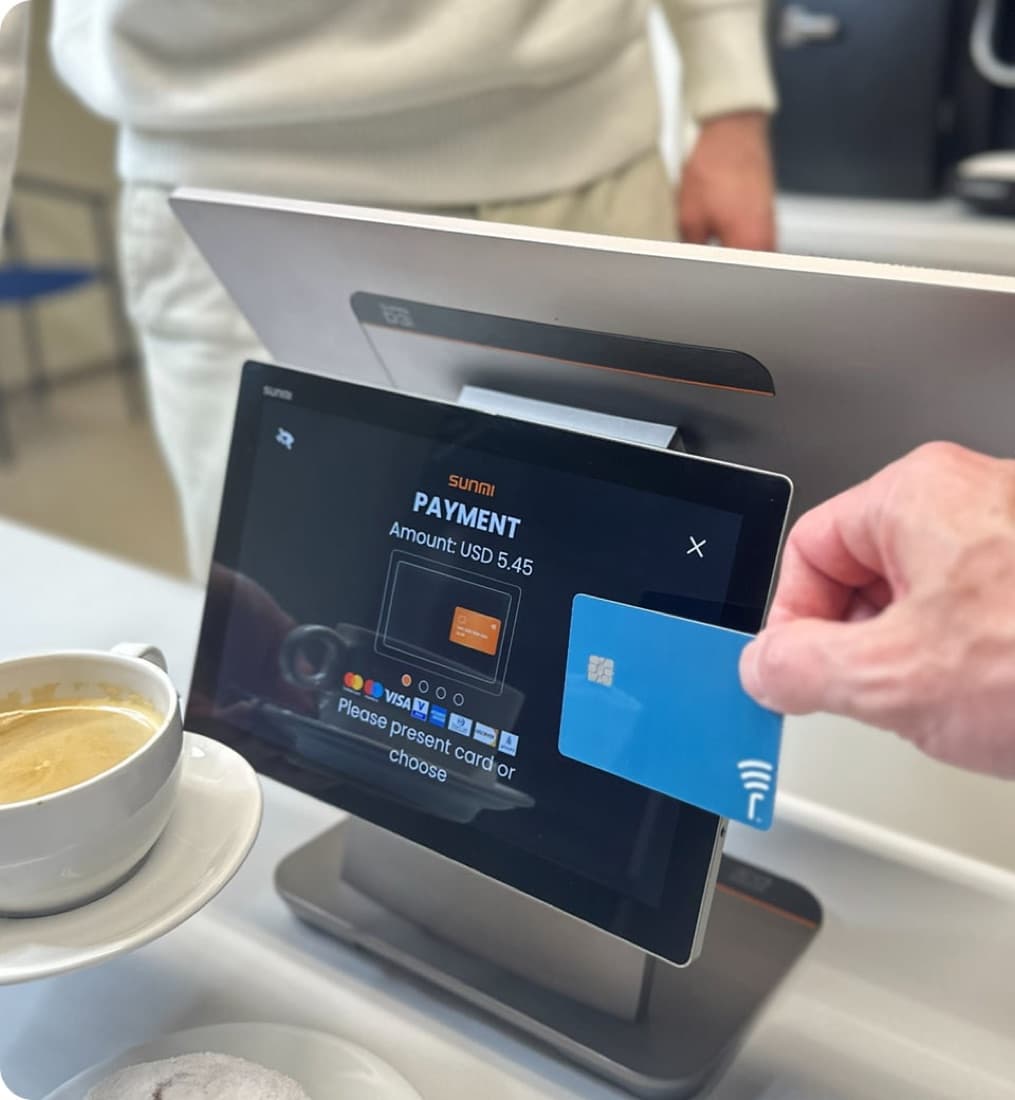 A SUNMI T3 desktop point-of-sale on a café counter accepting a contactless card.